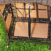 Close-up view of the underside of a wicker chair, showing the mechanical lift mechanism and frame, set against a grassy background. Produktbild-Vorschau