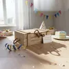 A wooden box is placed on a table with birthday decorations, including a cake, party hats, and confetti. Náhľad obrázku produktu