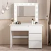 A white vanity table with a lighted mirror and drawers, decorated with makeup and flowers. Podgląd zdjęcia produktu