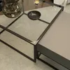 A close-up view of a modern coffee table with glass and metallic elements. Produktbild-Vorschau