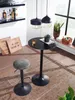 A bar stool and table set in a room with shelves of bottles and plants. Produktbild-Vorschau