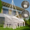 A beige macrame hammock chair with cushions hanging in a garden with a house in the background. There are two circular insets showing the chair rotating and swaying. Náhled obrázku produktu