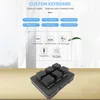 A close-up of a black custom keyboard with six keys, set against a blurred background with text and icons describing its features. Produktbild-Vorschau