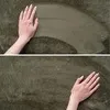 A close-up of a hand touching a green carpet. Produktbild-Vorschau