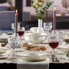 A formal dining table setting with candles, wine glasses, plates, and bread. Náhľad obrázku produktu