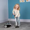 A young girl is playing with a toy vacuum cleaner in a room. Náhled obrázku produktu
