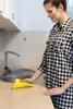 A woman is cleaning a kitchen counter with a yellow sponge. Náhled obrázku produktu