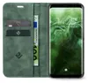 A green flip cover phone case with cards and a banknote inside, next to a smartphone displaying the time and date. Produktbild-Vorschau
