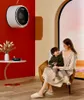 A woman and child sitting in a chair in a modern living room, with a washing machine mounted on the wall. Produktbild-Vorschau