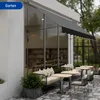 An outdoor seating area of a cafe or restaurant with tables, chairs, and a sofa under an awning. Náhľad obrázku produktu
