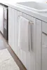 A towel hanging on a holder attached to a white wooden cabinet next to a sink. Náhľad obrázku produktu