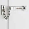 A close-up view of a silver door chain lock mounted on a white door. Produktbild-Vorschau