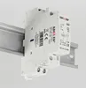 A white electrical component, likely a relay or contactor, is mounted on a metal DIN rail. The background is plain white and light gray. Produktbild-Vorschau