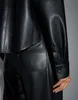 Close-up of a person wearing black faux leather pants and a black faux leather shirt. Produktbild-Vorschau