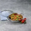 A stainless steel serving pan filled with ratatouille, placed on a gray surface next to a red pepper and some herbs. A glass lid rests on a blue cloth to the left. Podgląd zdjęcia produktu