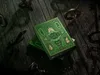 Two decks of green and gold playing cards with 'Wicked' printed on them, placed on a dark wooden surface with antique keys scattered around. Náhled obrázku produktu