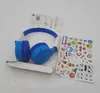A pair of blue and white headphones are laid out with a set of stickers and an instruction manual. Produktbild-Vorschau