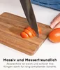 A person is slicing a tomato on a wooden cutting board. Náhled obrázku produktu