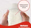 Hands holding a diaper with a callout box describing its features. Produktbild-Vorschau