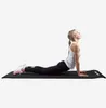 A woman is doing a yoga pose on a black yoga mat. Náhľad obrázku produktu