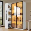 A white display cabinet with glass doors and LED lighting, showcasing various items on its shelves. A smaller white cabinet with shelves of books is attached to the left side. Produktbild-Vorschau