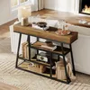 A console table with shelves is placed in a living room setting, next to a sofa and in front of a fireplace. Náhled obrázku produktu