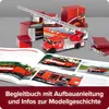 A collection of red model fire trucks and boxes, with an open book showing images of fire trucks. Produktbild-Vorschau