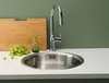A stainless steel sink with a faucet, cutting board, and grapes on a countertop. Produktbild-Vorschau