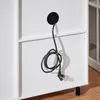 A close-up view of the back of a white cabinet with a black cable and plug emerging from a circular cutout. Produktbild-Vorschau