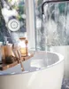 A bathroom scene with a bathtub filling with water, featuring bath accessories and a Bluetooth speaker on the window. Voir les images du produit
