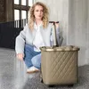 A woman is crouching next to a shopping trolley in an indoor setting. Voir les images du produit