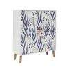 A white cabinet with a floral pattern and wooden legs, shown against a white background. Náhled obrázku produktu