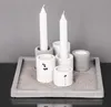 A set of concrete candle holders with white candles on a concrete tray filled with sand. Podgląd zdjęcia produktu