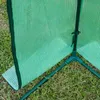 A close-up view of the corner of a green greenhouse made of mesh material, showing the frame and the ground. Podgląd zdjęcia produktu