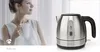 A woman holding a mug next to a kettle. Anteprima dell’immagine prodotto