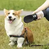 A corgi dog is sitting on grass while a person holds a portable water bottle for dogs. Náhľad obrázku produktu