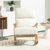 A cream-colored rocking chair with wooden legs is placed on a rug in a well-lit room. A small side table with a cup and saucer is visible to the right. Produktbild-Vorschau