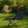 A black rocking chair is placed on a green lawn in a garden setting. A hammock is visible in the background. Produktbild-Vorschau