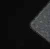 A close-up view of the corner of a black rug with a circular pattern on its underside. Produktbild-Vorschau