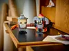 Two LEGO BrickHeadz figures, Gandalf the Grey and a Balrog, are displayed on a dark surface, possibly a desk, with art supplies in the background. Produktbild-Vorschau