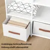 A white fabric storage drawer with brown leather handles, filled with folded clothes, placed within a white shelving unit. Náhľad obrázku produktu