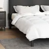 A white duvet on a bed with a black headboard. Produktbild-Vorschau