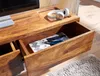 A close-up view of a wooden TV stand with an open drawer, showing some items inside and a pair of headphones on top. Produktbild-Vorschau