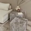 A living room scene with a sofa, two marble-look coffee tables, and decorative items. Produktbild-Vorschau