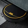 A black robot vacuum cleaner with gold accents is partially under a gray upholstered piece of furniture, on a patterned rug. Anteprima dell’immagine prodotto