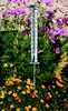 A thermometer is placed in a garden surrounded by flowers. Náhľad obrázku produktu