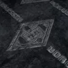 A close-up of a dark gray blanket with an embossed diamond logo and repeating text. Produktbild-Vorschau