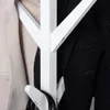 A close-up view of a white coat rack with two coats hanging on it. Produktbild-Vorschau