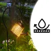 A solar-powered watering can lamp is illuminated at night in a garden, with water appearing to stream from its spout. Anteprima dell’immagine prodotto