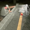 A person is working on a construction project, possibly laying bricks or concrete blocks, with tools and materials around them. Produktbild-Vorschau